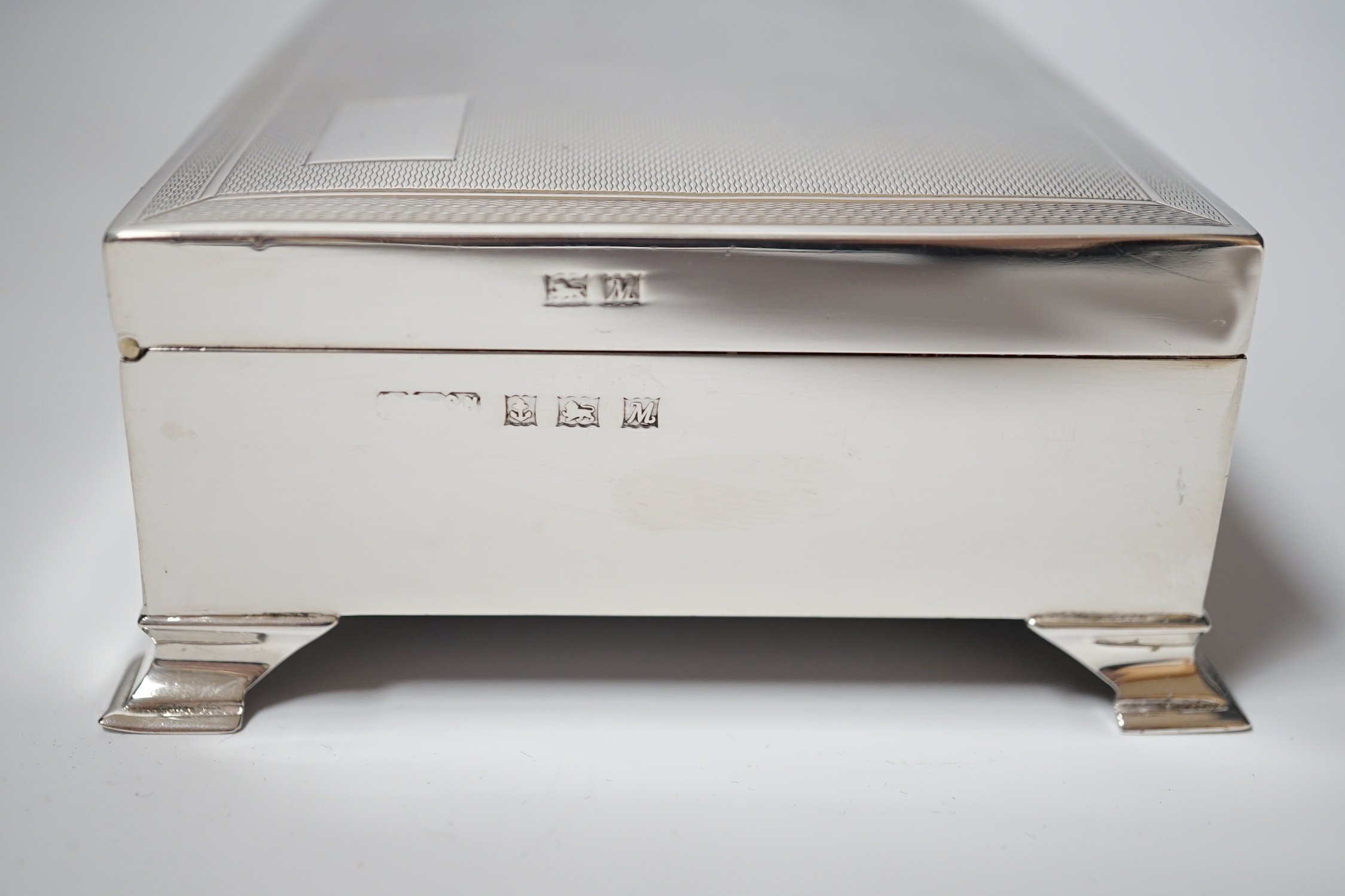 An Elizabeth II engine turned silver mounted rectangular cigarette box, Birmingham, 1961, 15.4cm, on bracket feet.